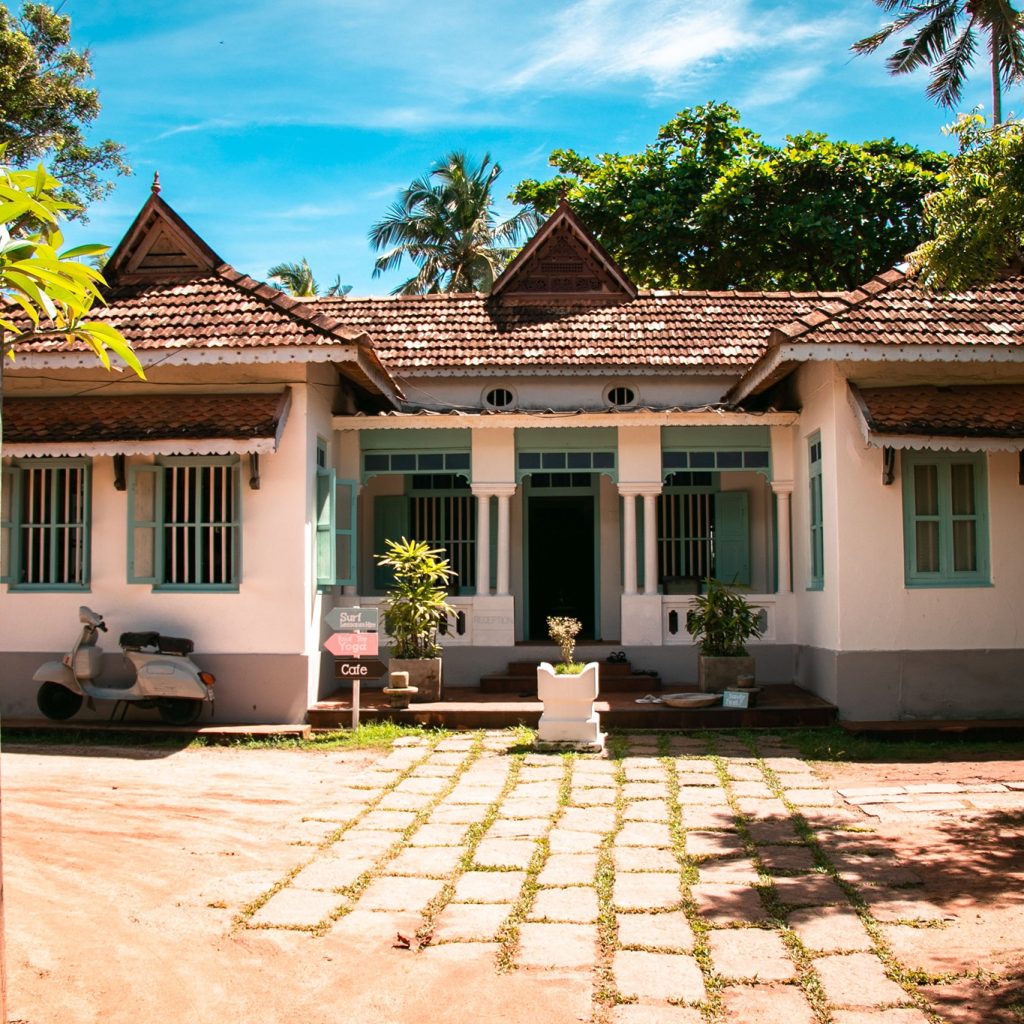 Traditional Kerala house with tiled roof and cafe sign in courtyard