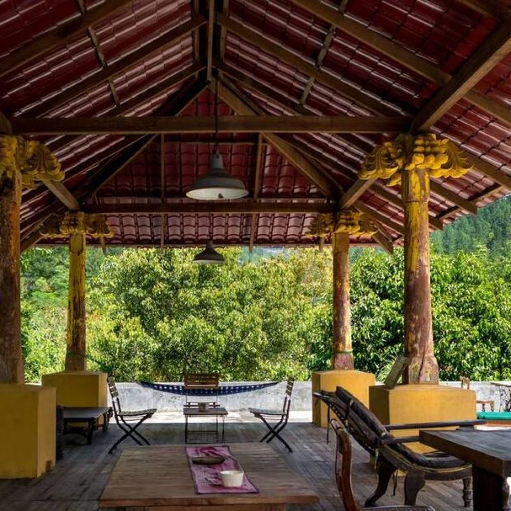 Open wooden pavilion with tiled roof overlooking lush greenery