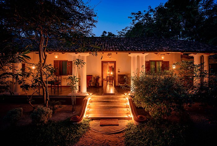 Traditional villa lit with lanterns at dusk, lush garden in front